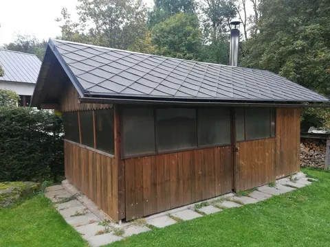 Dřevěný prosklený altán s komínem na trávníku