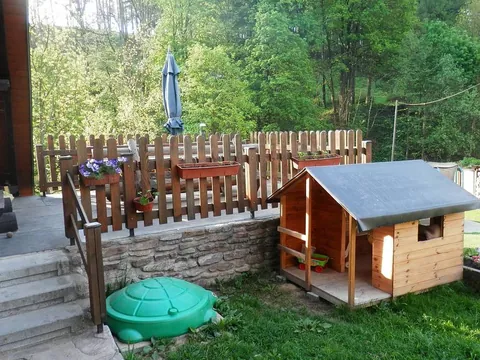 Dřevěný dětský domeček a pískoviště ve tvaru želvy u terasy
